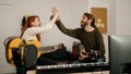 Man and woman playing guitar high five at music studio Royalty Free Stock Photo