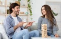 Man and woman playing Jenga at living room at home