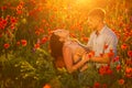 Man and woman in poppy field at sunset, romance Royalty Free Stock Photo