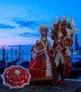 Man and woman pose in ornate, detailed costume, mask and hat with San Giorgio in the background during Venice Carnival, Italy. Royalty Free Stock Photo