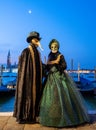 Man and woman pose in ornate, detailed costume, mask and hat with San Giorgio in the background during Venice Carnival, Italy. Royalty Free Stock Photo