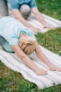 Man and woman practicing relaxation yoga poses on yoga mats in park