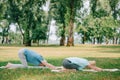 Man and woman practicing relaxation yoga poses on yoga mats on lawn
