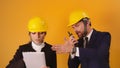 Man and woman professional architects with hard hats, tablet and walkie talkie isolated on orange background Royalty Free Stock Photo