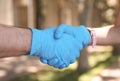 Man and woman in protective gloves shaking hands to say hello outdoors, closeup Royalty Free Stock Photo