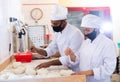 Man and woman in protective mask prepare bread in the kitchen of bakery Royalty Free Stock Photo