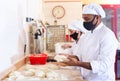 Man and woman in protective mask prepare bread in the kitchen of bakery Royalty Free Stock Photo