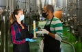 Man and woman in protective masks check the quality of white wine at winery Royalty Free Stock Photo