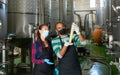 Man and woman in protective masks check the quality of white wine at winery Royalty Free Stock Photo