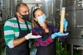 Man and woman in protective masks check the quality of white wine at winery Royalty Free Stock Photo