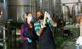 Man and woman in protective masks check the quality of white wine at winery Royalty Free Stock Photo
