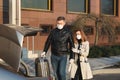 Man and woman in protective medical masks and gloves leave the house by car during the quarantine. Royalty Free Stock Photo