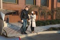 Man and woman in protective medical masks and gloves with a suitcase leave the house by car during the quarantine and Royalty Free Stock Photo