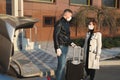 Man and woman in protective medical masks and gloves with a suitcase leave the house by car during the quarantine and Royalty Free Stock Photo