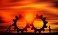 Man and Woman Pushing Gears At Sunset Orange sky. Business Persons Collaborate Together to Connect The Cogwheels.