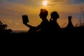 Man and woman reading in the park against sunset. Silhouette of couple reading book at sky sunset . warm tone and soft focus. Royalty Free Stock Photo