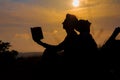 Man and woman reading in the park against sunset. Silhouette of couple reading book at sky sunset . warm tone and soft focus. Royalty Free Stock Photo