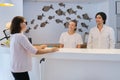 Man and woman receptionists at the workplace. Guest checking in at front desk