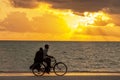 Man with woman riding by bicycle at sunset along the ocean coast, Zanzibar Tanzania. Royalty Free Stock Photo