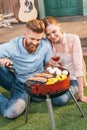 Man and woman roasting meat and vegetables on barbecue grill Royalty Free Stock Photo