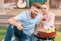 Man and woman roasting meat and vegetables on barbecue grill Royalty Free Stock Photo