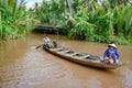 Vietnamese couple paddling on wooden boat at tributary river of Mekong River, near Ho Chi Minh City, Vietnam