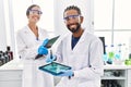 Man and woman scientist partners looking embryo image on touchpad at laboratory