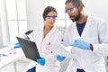 Man and woman scientist partners reading documents at laboratory