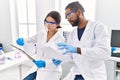 Man and woman scientist partners reading documents at laboratory