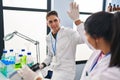 Man and woman scientists partners high five with hands raised up at laboratory Royalty Free Stock Photo