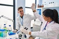 Man and woman scientists partners high five with hands raised up at laboratory Royalty Free Stock Photo