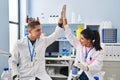 Man and woman scientists partners high five with hands raised up at laboratory Royalty Free Stock Photo