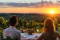 A couple relaxes at a table, gazing at the sunset over the horizon Royalty Free Stock Photo