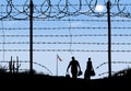 A man and woman are seen in silhouette after breaching a border fence Royalty Free Stock Photo