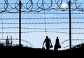 A man and woman are seen in silhouette after breaching a border fence Royalty Free Stock Photo