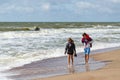 Man and woman are on shore of beach on Baltic Sea in sunny windy
