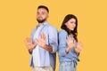 Couple gesturing stop with hands, standoffish poses, yellow background Royalty Free Stock Photo