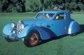 A man and woman sit in a blue Bugatti automobile at a vintage car show in Pebble Beach, California, ca. 1985. Royalty Free Stock Photo