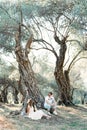 Man and woman sit on the roots of an old olive tree and look at each other Royalty Free Stock Photo