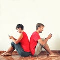 Man and woman sitting back to back and looking at their smartphones. Gadgets replace live communication. Square, copy space