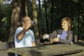 Man and woman sitting on a bench rehydrating with water in a metal cup after trekking in the mountains