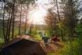 Man and woman sitting in chairs outside the tent, drink beer, clink bottles. Couple camping in forest. Happy couple on a camp trip Royalty Free Stock Photo