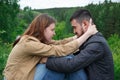 A man and a woman are sitting on a hill facing each other