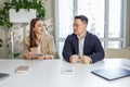 Man and woman sitting in office, holding money at hands. Gender pay gap, unequal salary concept