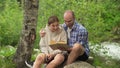 A man and a woman are sitting on a rock. A man is reading a book with a friend. A boy and a girl have a date. In the Royalty Free Stock Photo