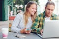 Man and woman sitting in street cafe with laptop and mobile phone, cheerful couple Royalty Free Stock Photo