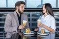 A man and a woman are sitting at a table in a cafe, holding drinks Royalty Free Stock Photo