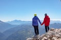 Man and woman stand holding hands on the edge of a cliff overlooking the mountains Royalty Free Stock Photo