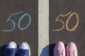 A man and a woman stand on opposite sides of a 50/50 chalk line on the asphalt. The concept of gender equality Royalty Free Stock Photo