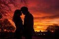 A man and a woman standing side by side, enjoying the breathtaking view of a sunset, couple sharing a kiss against a colourful